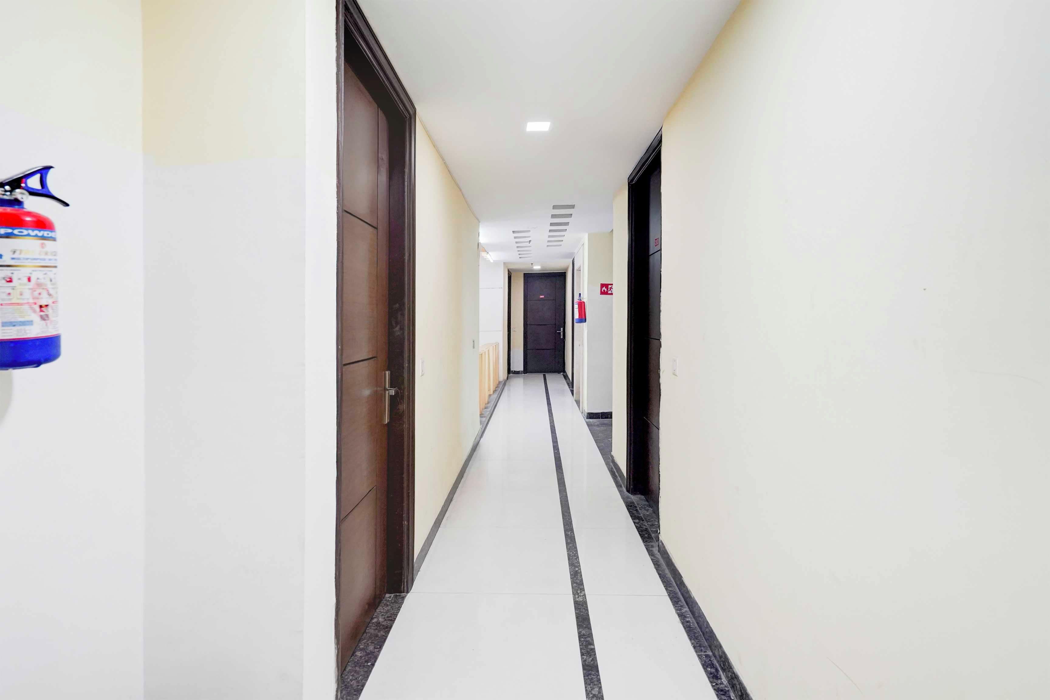 A corridor with doors on both sides, a fire extinguisher on the left, and a fire hose on the right.