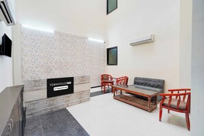 A reception area with a reception desk, a sofa, chairs, a coffee table, and a flat-screen TV. - Townhouse Oak Sector 51 Noida (Noida)