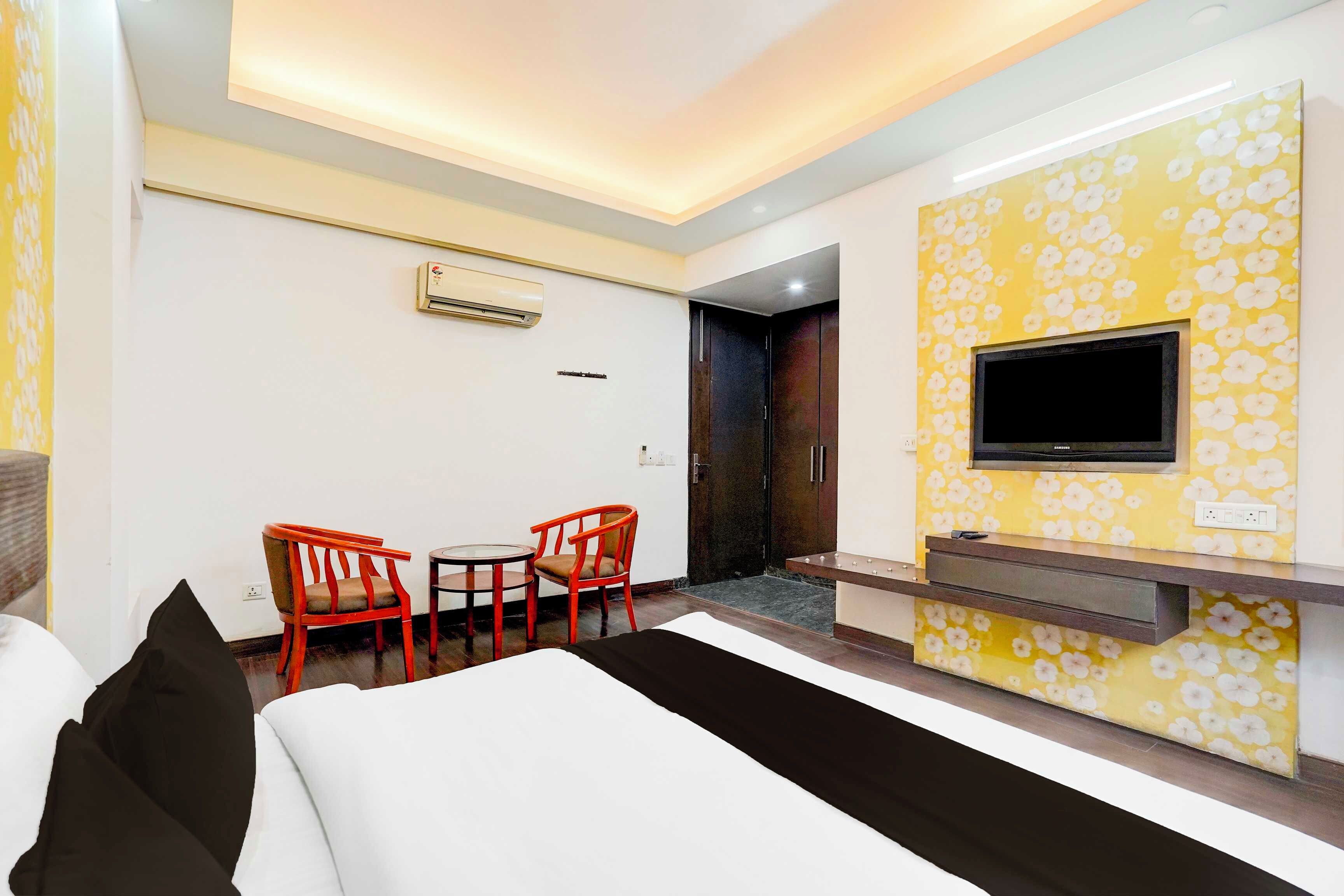 Habitación de hotel con cama, televisión montada en la pared, escritorio con silla y equipo de aire acondicionado.