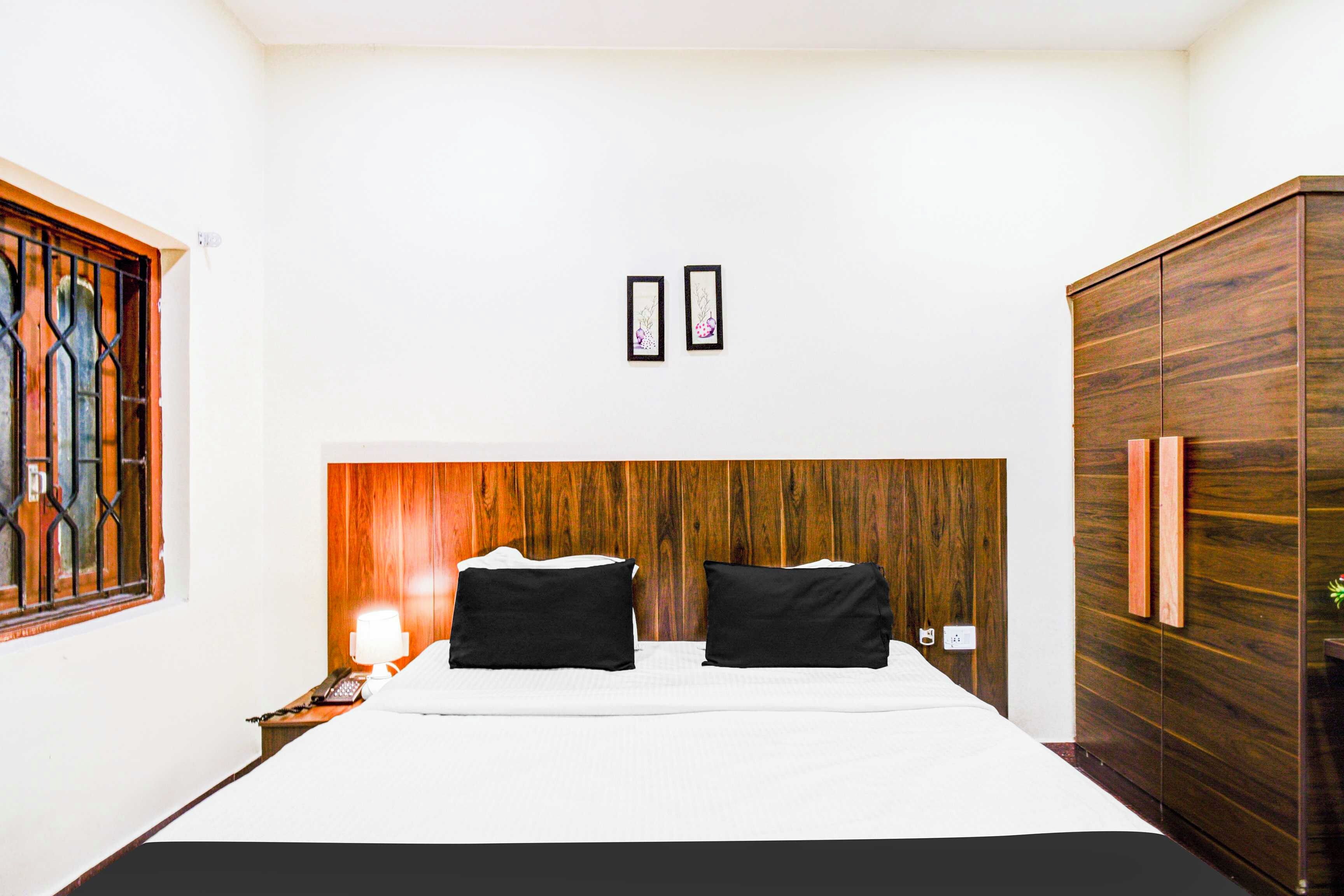 Une chambre à coucher avec un lit, une table de chevet, une lampe, une armoire et une fenêtre avec des barreaux.