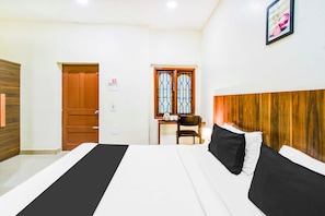 Habitación de hotel con cama, cabecera de madera, escritorio con silla y ventana con barrotes.