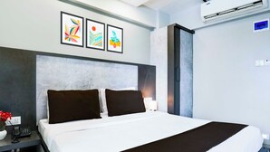 Moderni hotellihuone, jossa on suuri sänky, yöpöytä, jossa on puhelin, ja seinälle asennettu ilmastointilaite.