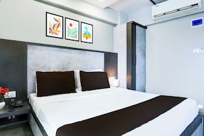 Una habitación de hotel moderna con una cama grande, una mesita de noche con teléfono y un aire acondicionado instalado en la pared.