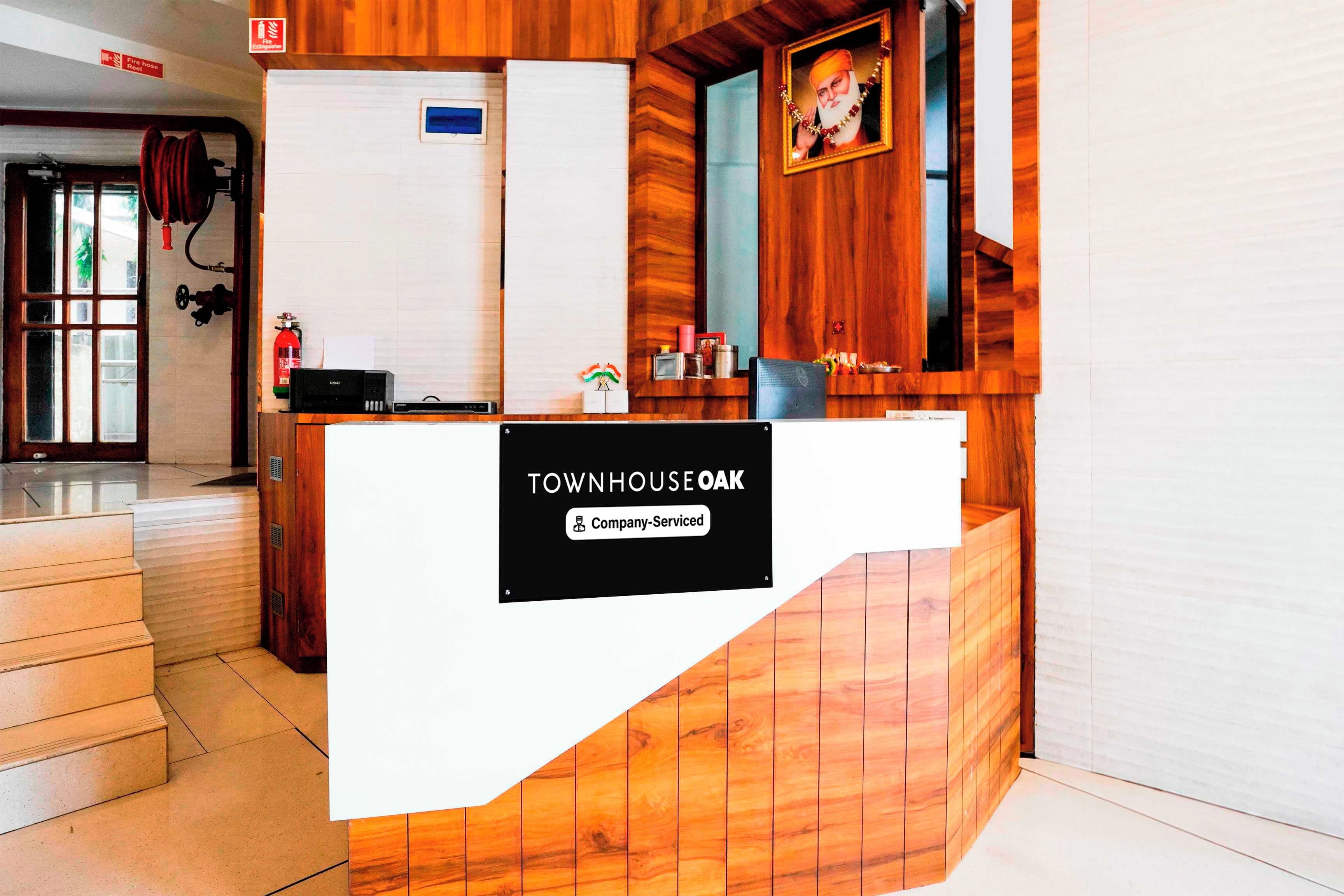 Un comptoir d’accueil avec une pancarte indiquant « TOWNHOUSE E OAK » et « Services aux entreprises ».