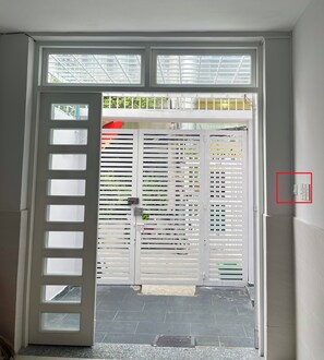 A white door with multiple windows, a tiled floor, and a visible electrical outlet on the wall. - Oula Home - Tea Studio l Central D1, 5 Mins to Ben Thanh Market (Thành phố Hồ Chí Minh)