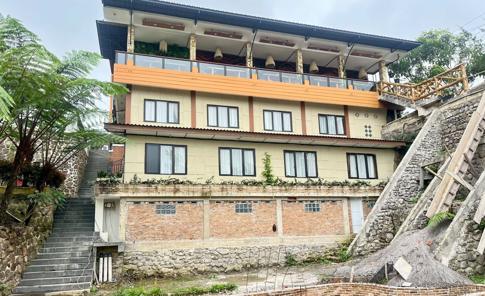 Um edifício com vários andares, varanda, escadaria e parede de pedra.