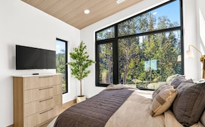 Large windows surround this peaceful sleeping space with views of the trees.