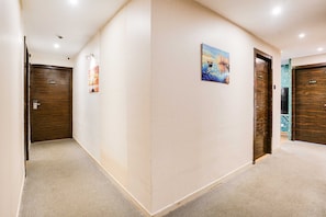 A hallway with three wooden doors, each marked with a number. - Townhouse Andheri Near Western Express (Mumbai)