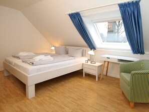 Ein Schlafzimmer mit einem Bett, einem Nachttisch, einer Lampe und einem Sessel.