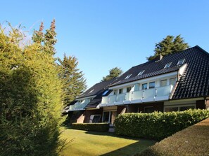 Un immeuble résidentiel doté d’un toit en pente, de nombreuses fenêtres et d’une pelouse bien entretenue.