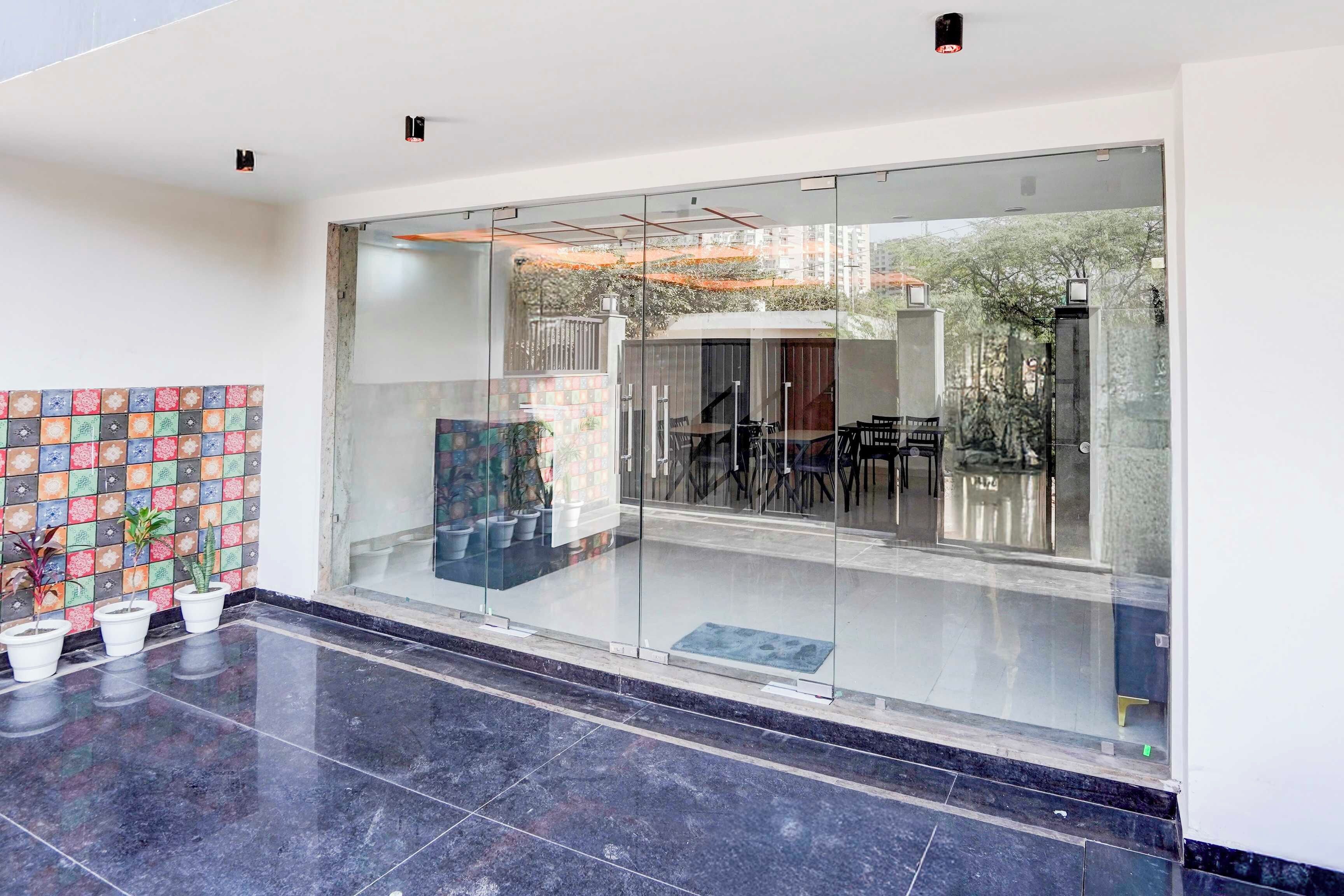 Un interior moderno con entrada de vidrio, pared de azulejos con un diseño colorido y plantas en macetas.