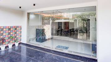 Un interior moderno con entrada de vidrio, pared de azulejos con un diseño colorido y plantas en macetas.
