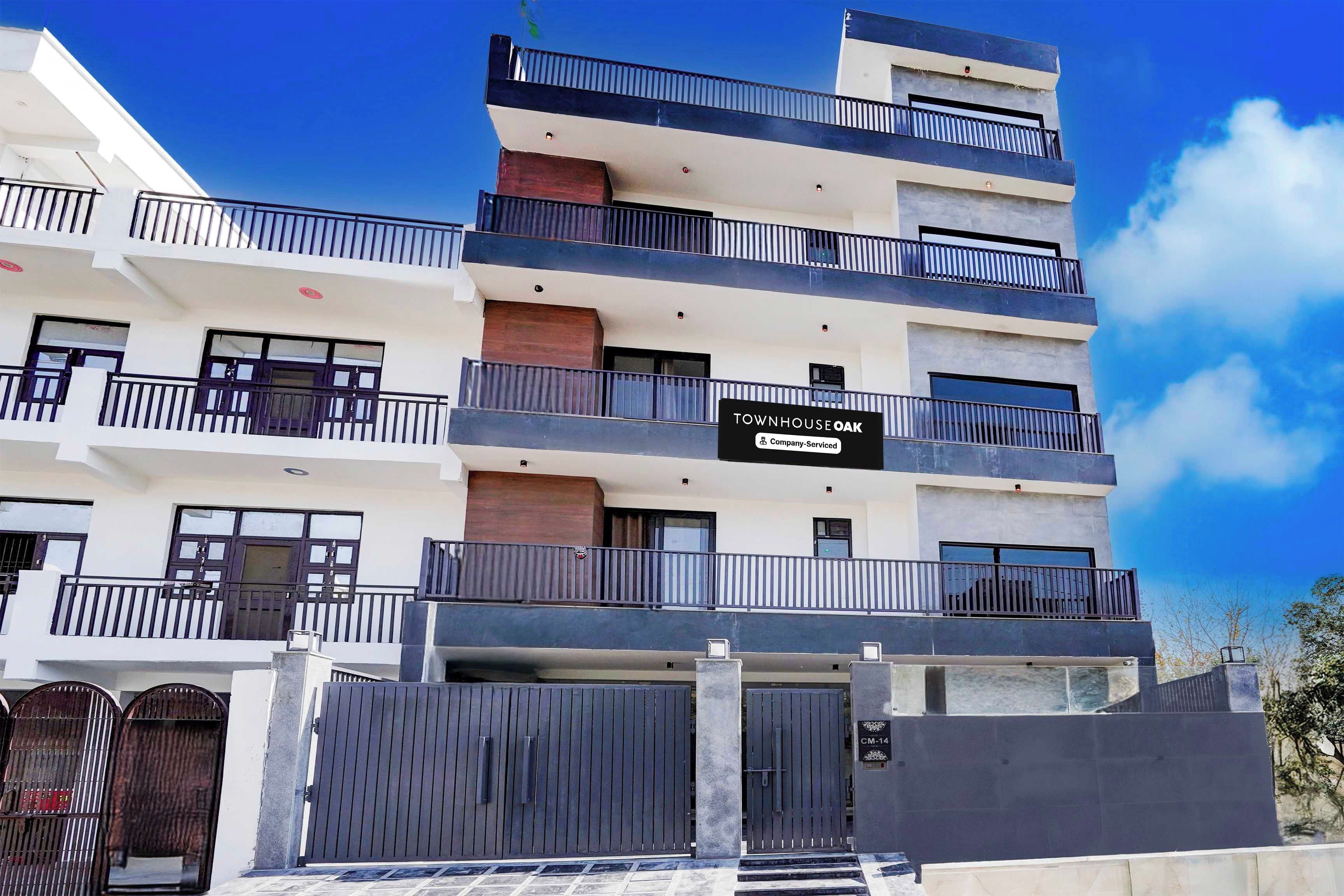 Un edificio residencial de varios pisos con balcones, una señal de servicio de la empresa y una entrada protegida por una reja.