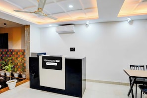 A reception desk with a sign indicating it is company-serviced. There is a ceiling fan, air conditioning unit, and a tiled floor. - Townhouse Oak Sector 143B Noida (Noida)