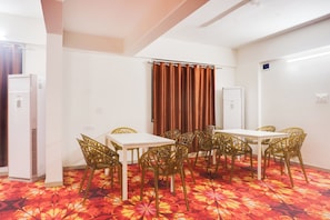 A conference room with a white table and chairs, a patterned carpet, and a curtain.