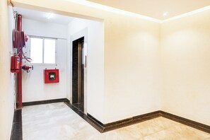 A hallway with a fire extinguisher, a red emergency box, and a door.