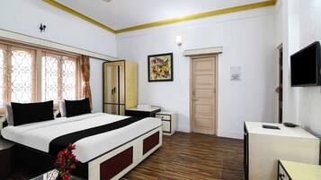 A hotel room with a bed, a desk, a television, and a wardrobe.
