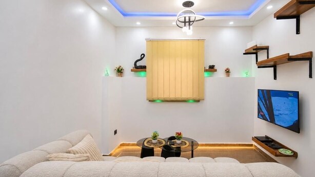 Una habitación moderna con sofá, televisor, lámpara de techo y paneles de madera.