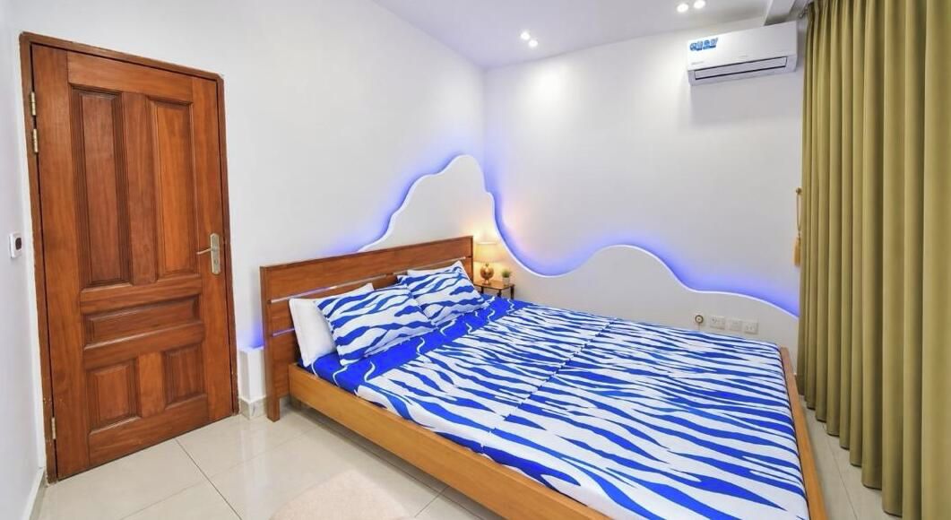 A bedroom with a wooden bed, a door, and an air conditioning unit.