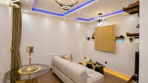 Una sala moderna con sofá, una mesita de vidrio y televisor.