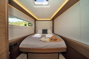 Ein kompakter, moderner Schlafzimmerraum mit Dachfenster, einem Bett mit Kopfteil, einem Fenster mit Aussicht und einem kleinen Nachttisch.