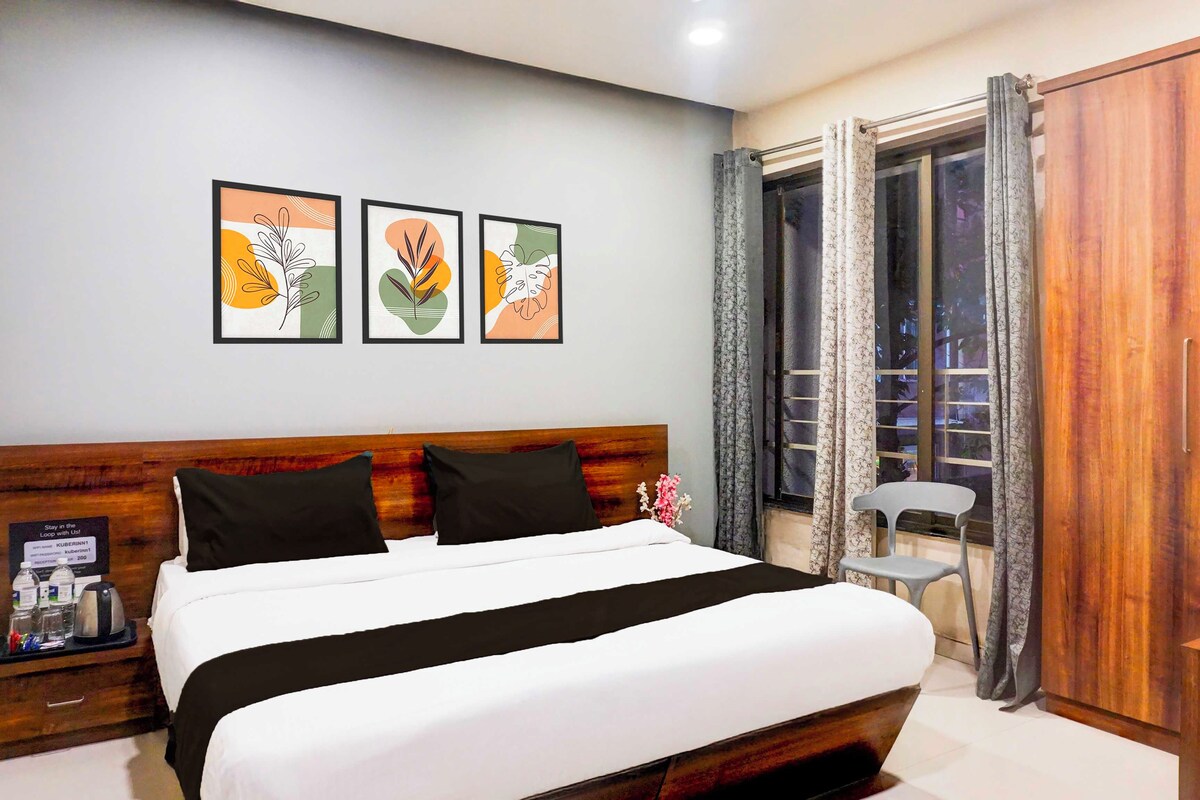 Una habitación de hotel con cama, mesita de noche, armario de madera y ventana con cortinas.