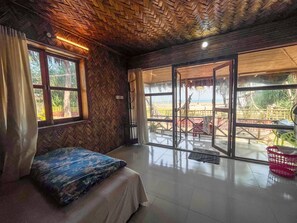 A room with a bed, large windows, and a view of the outside.