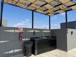 A rooftop outdoor area with a black sink, a fire extinguisher, and a trash bin. - Near the beach with a rooftop pool – By GPSRentas (Mazatlán)