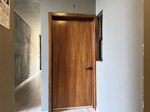 A hallway with a wooden door, a light switch, and a wall-mounted light fixture. - Near the beach with a rooftop pool – By GPSRentas (Mazatlán)