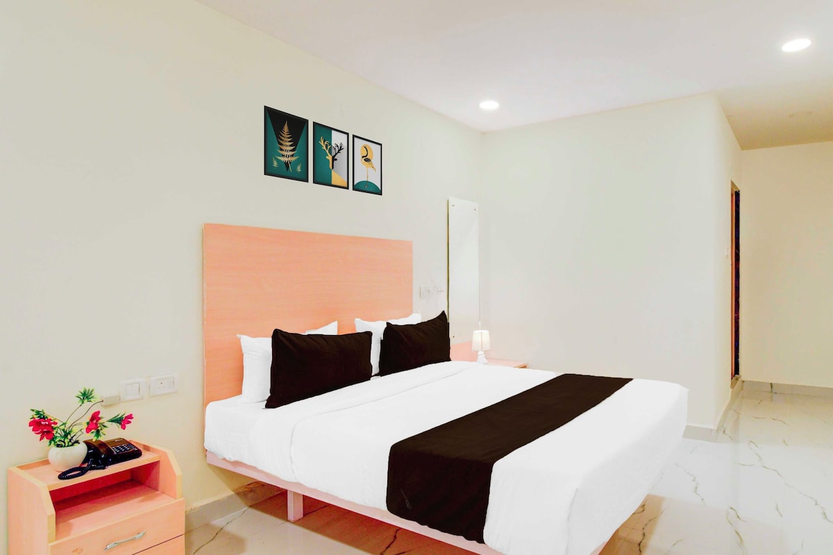 A hotel room with a bed, bedside tables, a nightstand, and a wall-mounted artwork.