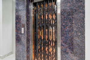 An elevator with a black metal gate and a marble wall. - Townhouse Oak Hyderabad Miyapur (Hyderabad)