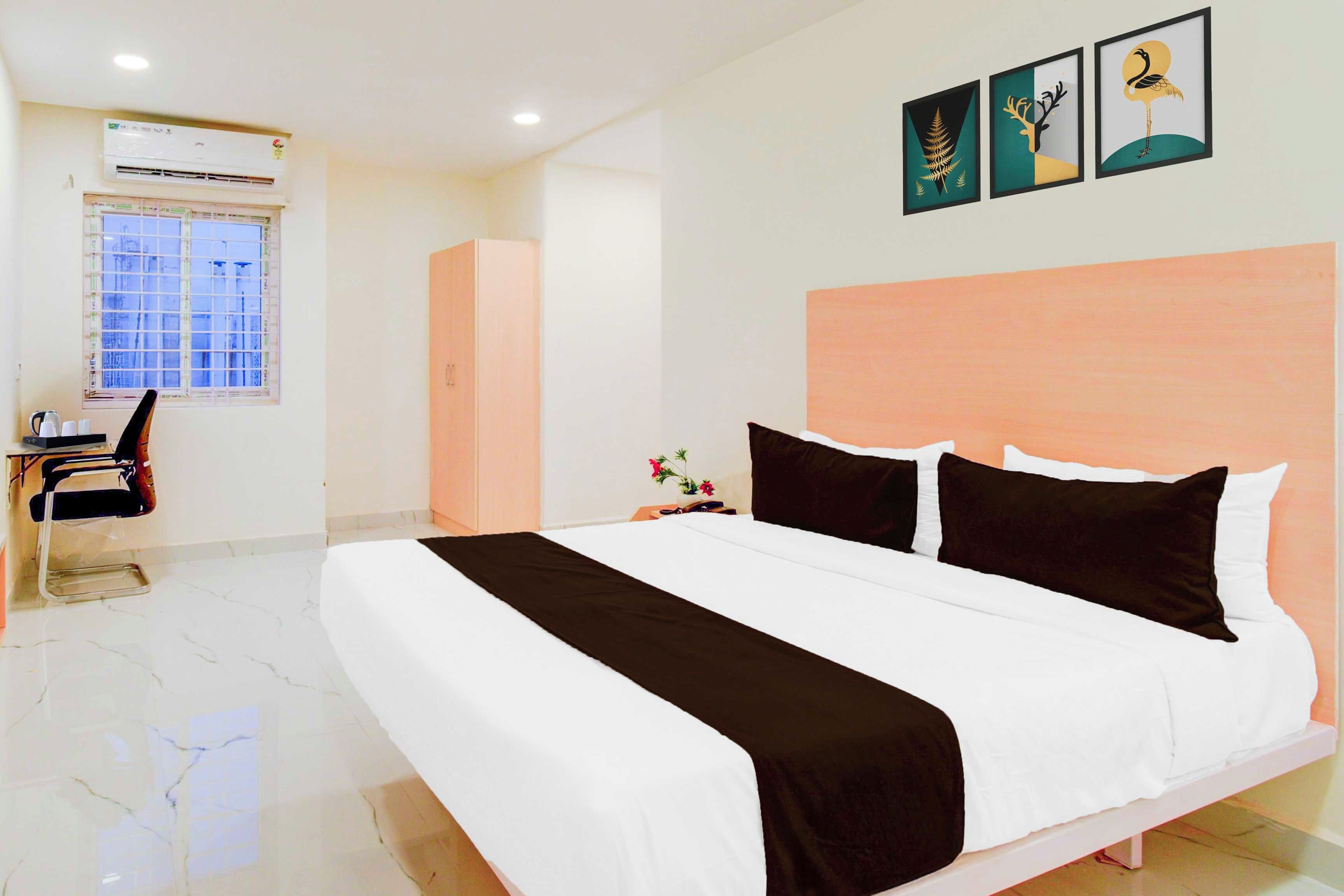 A hotel room with a bed, a desk, and a window.