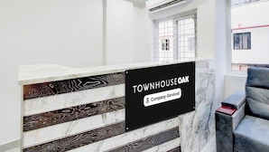 En receptionsdisk med marmorudsmykning, et skilt der viser 'TOWNHOUSE OAK & Company-Serviced' og et vindue med udsigt ud