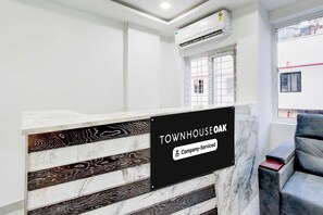 Una recepción con diseño de mármol, un letrero que indica 'TOWNHOUSE OAK & Company-Serviced' y una ventana con vistas al exterior.
