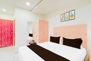 Una habitación de hotel con una cama grande, un armario, un espejo y obras de arte en la pared.