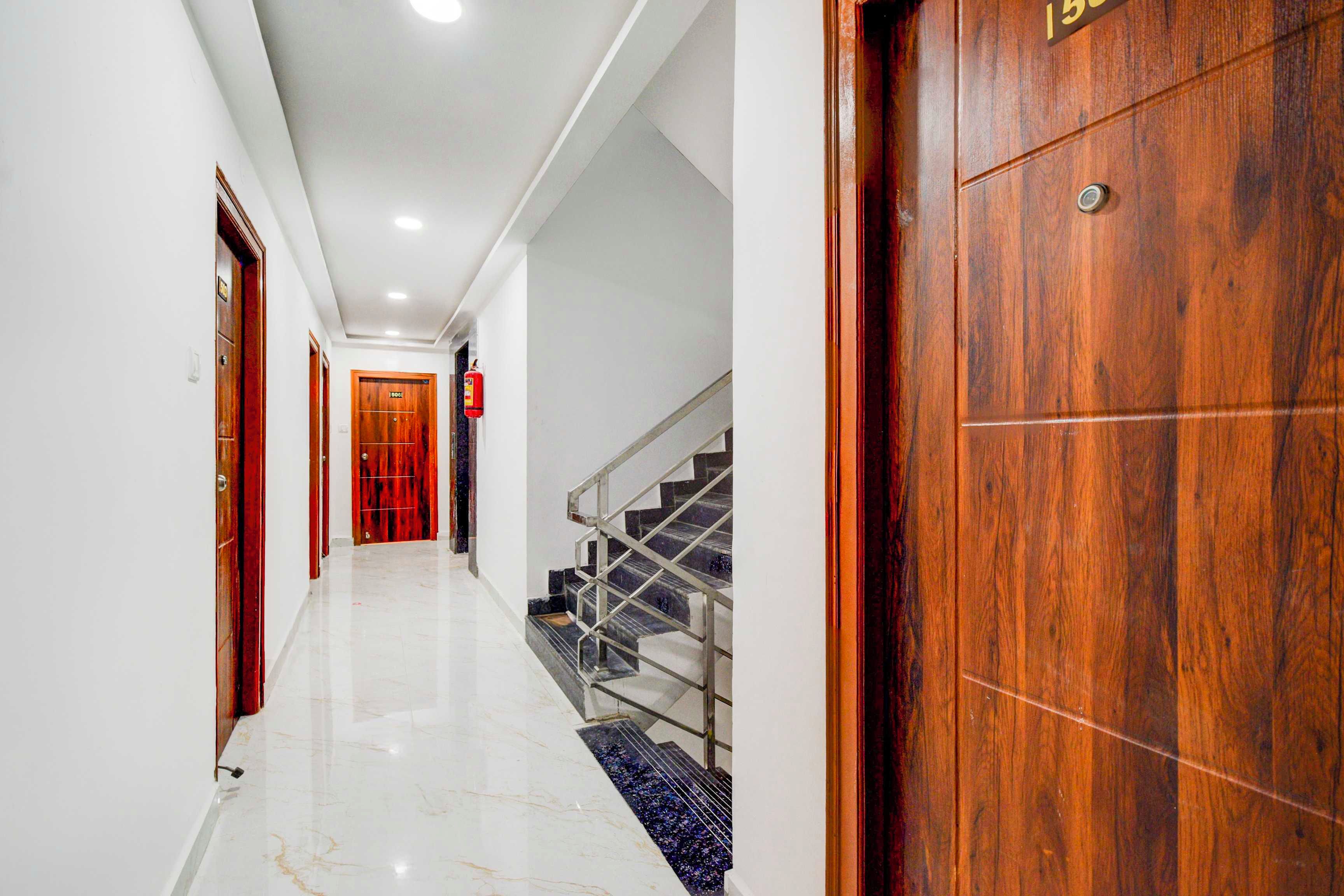 A hallway with a marble floor, wooden doors, and a staircase with metal railings.