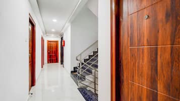 Un corridoio con pavimento in marmo, porte in legno e una scala con ringhiere in metallo.