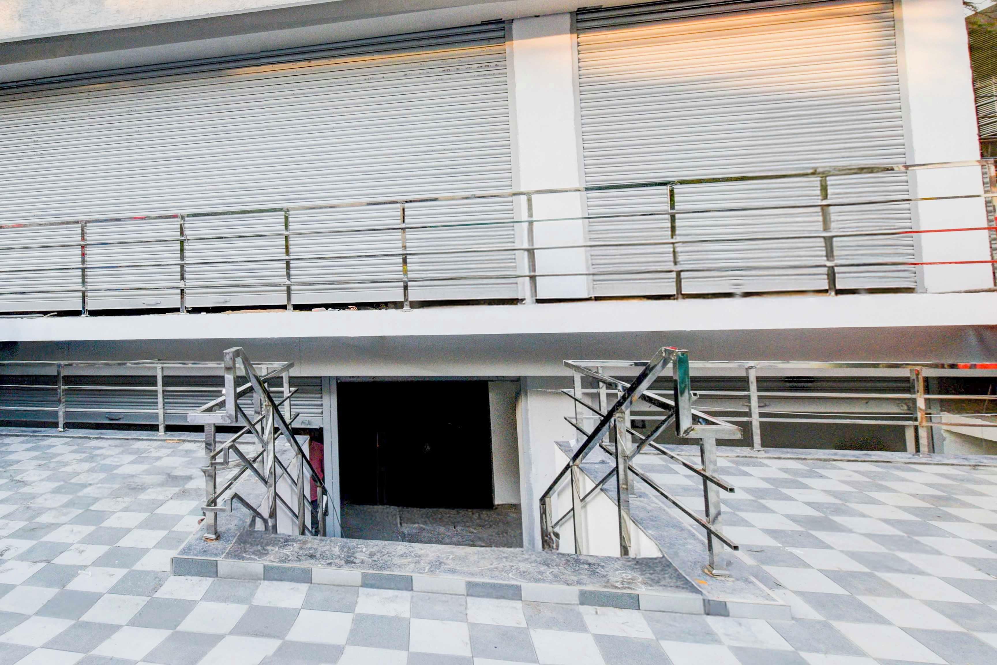 A building with a checkered floor pattern, metal staircases, and closed metal shutters on the upper level.