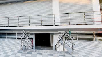 A building with a checkered floor pattern, metal staircases, and closed metal shutters on the upper level.