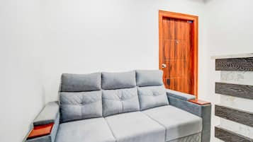 A grey sofa with a wooden frame and a wooden door in the background.