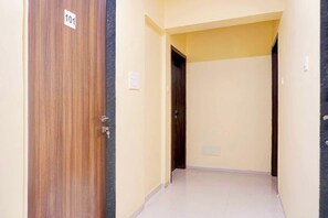 Corredor com porta de madeira identificada com o número '101' e um interruptor de luz na parede.