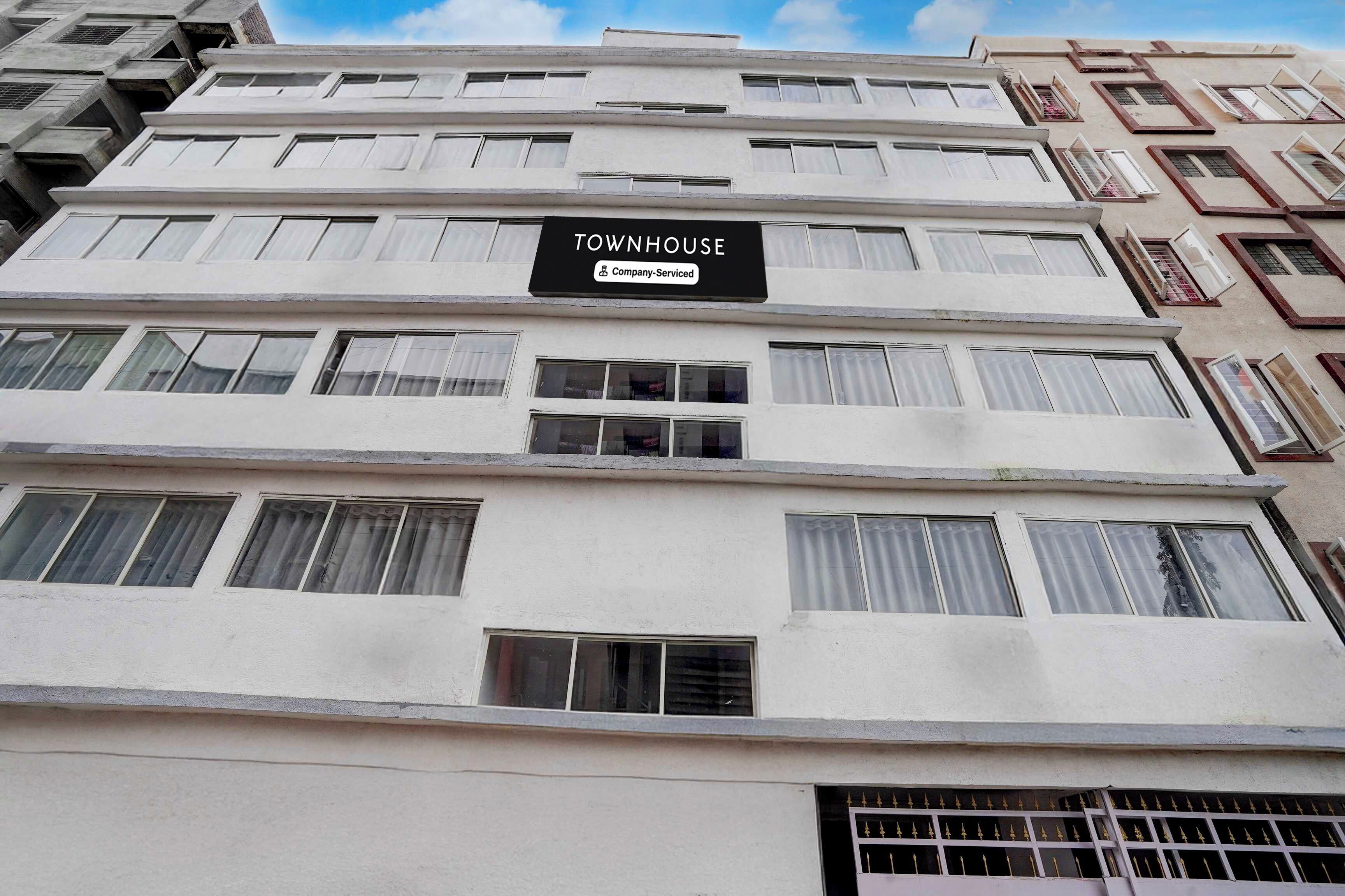 Un edificio de varios pisos con un letrero que dice 'TOWNHOUSE Company-Serviced'.
