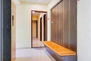 Un pasillo con un banco, una puerta y piso de baldosas.