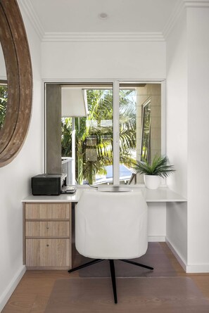 A modern office space with a desk, chair, printer, and a large window with a view of palm trees. - Boutique Top-Floor Riverfront Apartment (Noosaville)