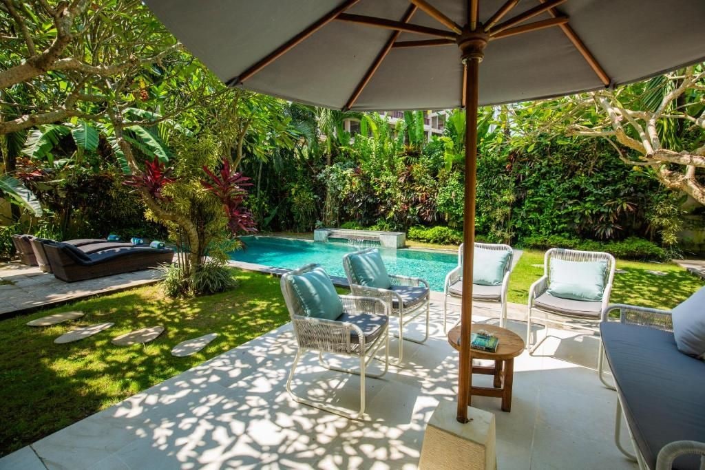 A poolside area with lounge chairs, a table, and an umbrella.
