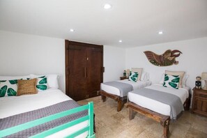 A bedroom with two beds, a wooden wardrobe, and a decorative wall piece. - 4 bedroom villa in Canggu, 2 minutes walk to the beach (canggu)