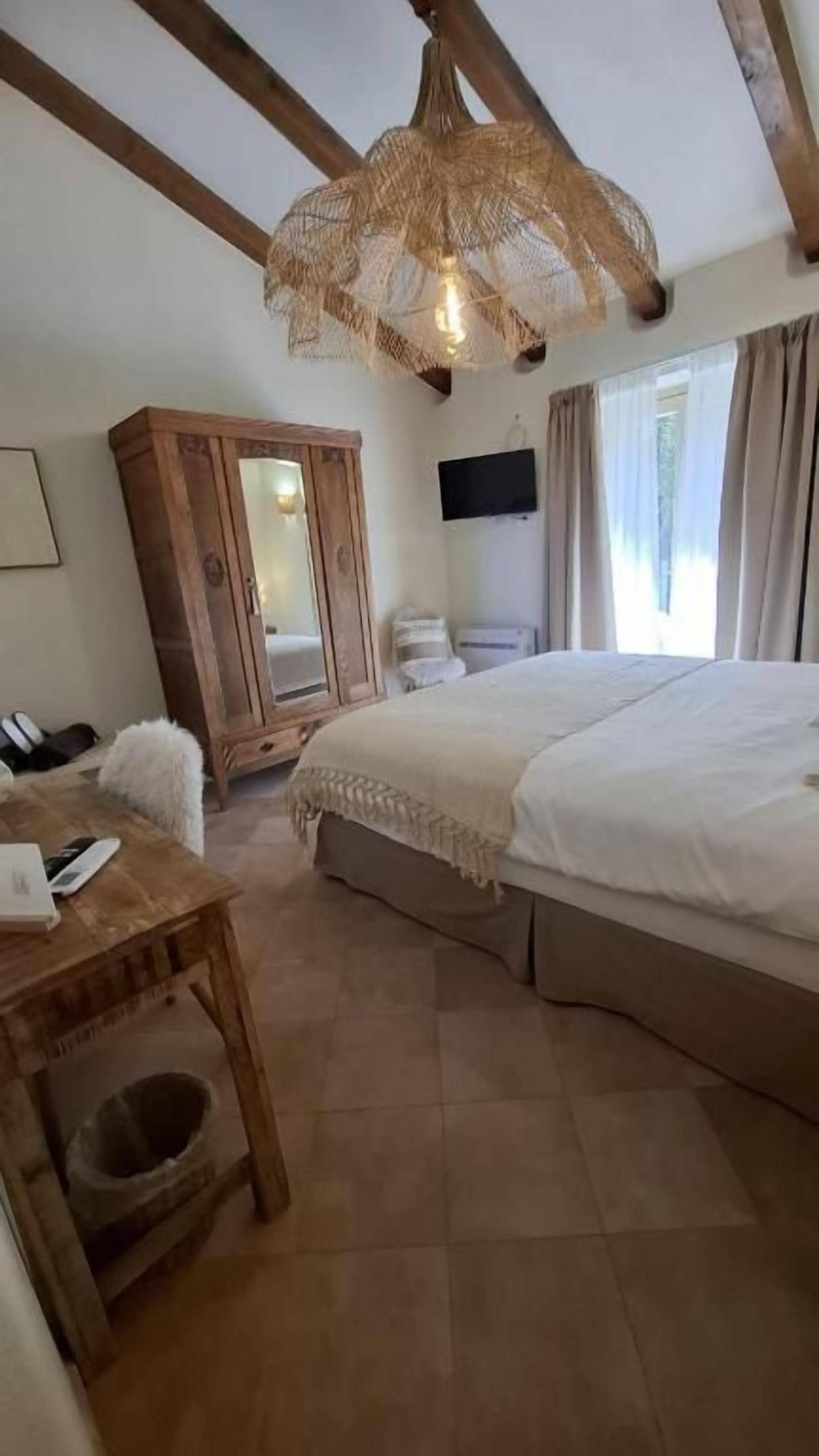 Ein Schlafzimmer mit einem großen Bett, einem Holzschrank und einer Pendelleuchte.