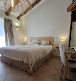 A bedroom with a large bed, bedside lamps, a wooden chair, and a woven ceiling light fixture. - Stazzu La Vigna di Maria (Luogosanto)