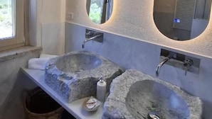 Un baño con dos lavamanos de piedra, una ventana y un espejo con iluminación integrada.