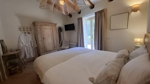 A bedroom with a large bed, a wardrobe, a television, and a window with curtains. - Stazzu La Vigna di Maria (Sardegna)